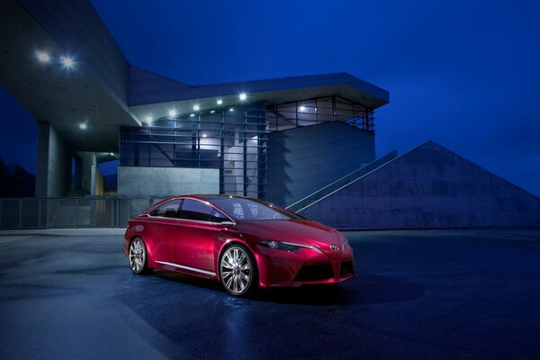 Voiture rouge vif sur le fond de la maison pendant la nuit