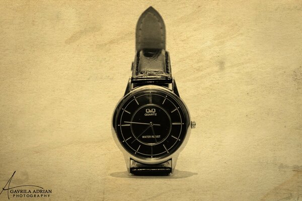Montre avec cadran noir et bracelet sur fond clair