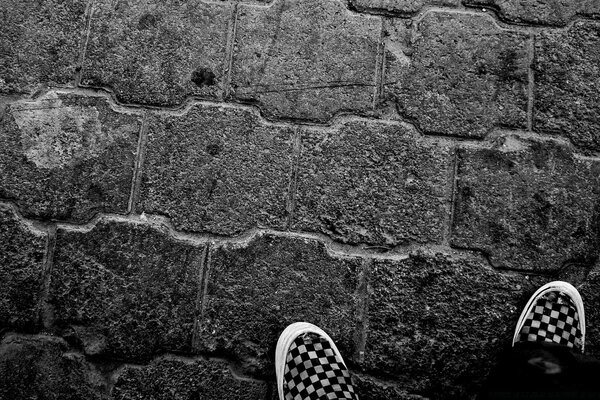 Pieds dans des baskets sur un mur de pierre