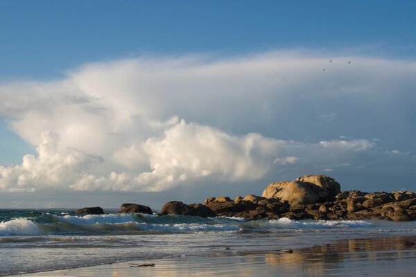Vagues sur la plage de sable sur fond de nuages